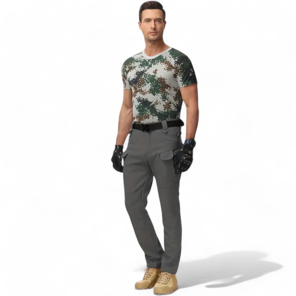 Man i grå Utility Fleece Pants med flera fickor och kamouflagemönstrad t-shirt