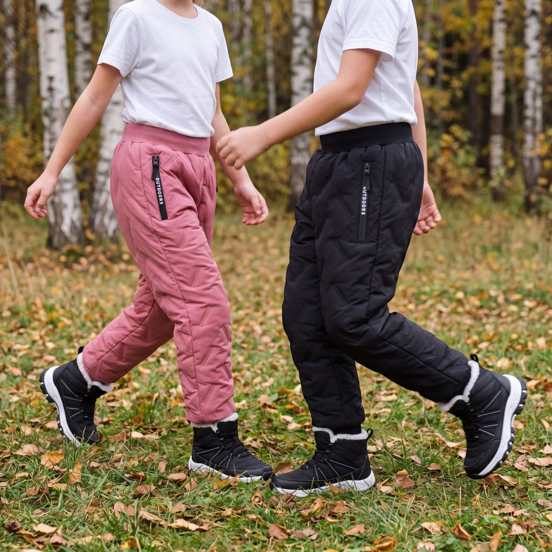 Två barn i Kids' Fleece Pants i rosa och svart som leker utomhus