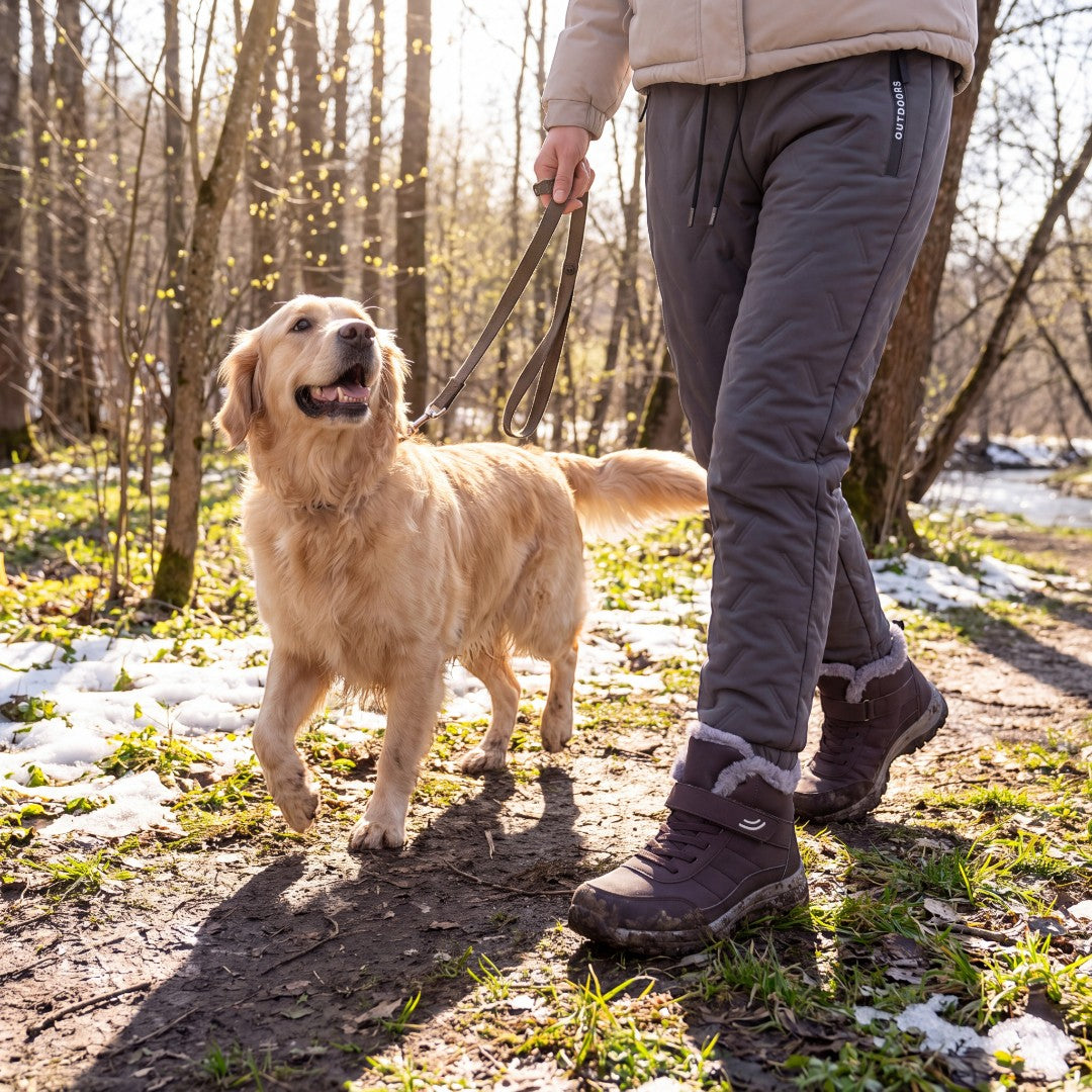 Pessoa com Warm Comfort Shoes a passear o cão num trilho com neve