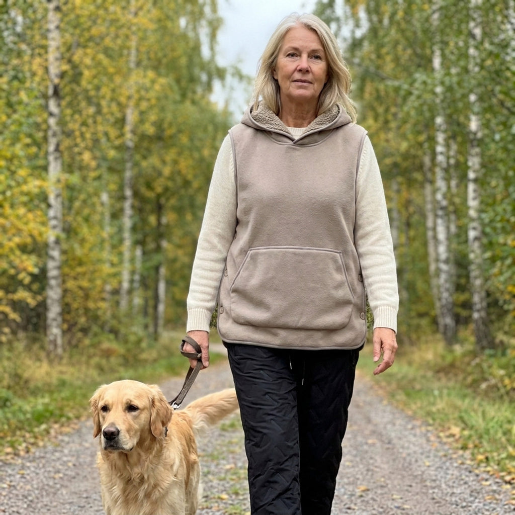 Kvinde omkring 60 på gåtur med hunden i en efterårsfarvet birkeskov i beige Sherpa Hoodie Vest og sorte Warm Fleece Pants